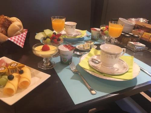 a table topped with plates of food and cups of orange juice at Cuerne bed&breakfast in Kuurne