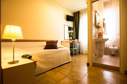 a bedroom with a bed and a bathroom with a sink at Hotel Roma in Pisa