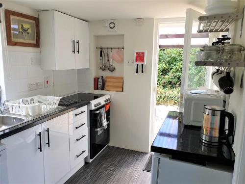 eine Küche mit weißen Schränken und einer schwarzen Arbeitsplatte in der Unterkunft Primrose Cottage in Moreton