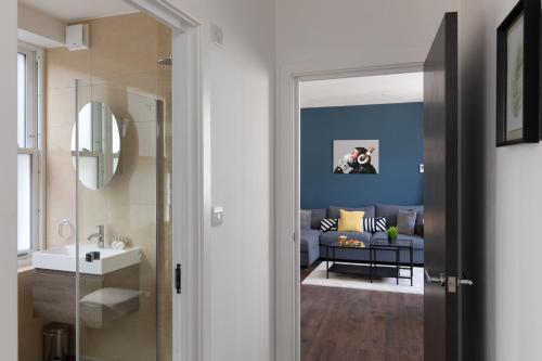 a bathroom with a sink and a living room at homely - Central London Liverpool Street Apartments in London