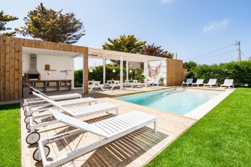 a backyard with a pool with lounge chairs and a house at Casa Vica - Sagres Apartments in Sagres