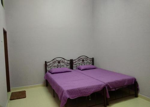 a bed in a room with a purple blanket at Homestay D ARYNIE in Bukit Payong