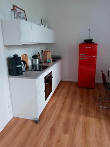 a small kitchen with a red refrigerator and wooden floors at Storchenhof in Wrestedt