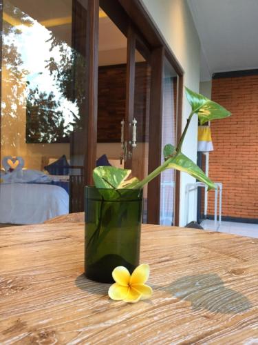 a vase with a yellow flower on a wooden table at Cahaya Guest House in Ubud