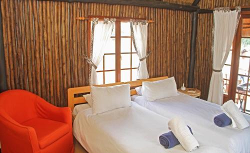a bedroom with two beds and a chair and a window at Camelthorn Kalahari Lodge in Hoachanas
