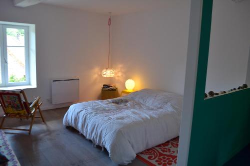um quarto com uma cama, uma cadeira e um candeeiro em Chambre privative et originale, à 20 mn de Cluny em Trivy