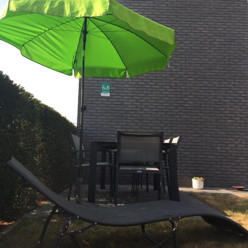 a table and chairs under a green umbrella at Holiday home Poire et Table in Wingene