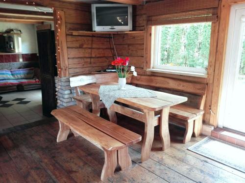 a dining room with a table and benches in a cabin at Brīvdienu māja"Jauneglites" in Skulte