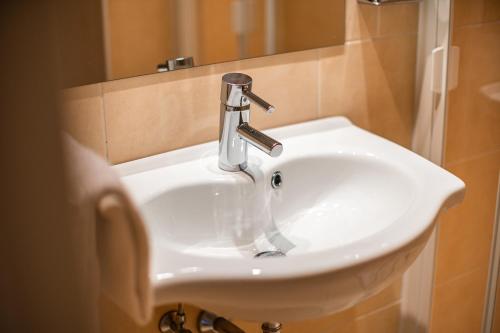 a white sink in a bathroom next to a mirror at Hotel Parks in Velden am Wörthersee