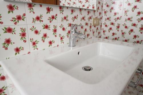 lavabo blanco en un baño con flores en la pared en B&B Casa Elena Room and Apartments with parking, en Gargnano