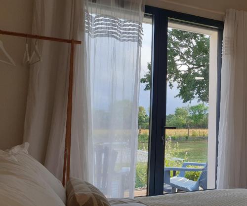 a bedroom with a bed and a large window at Le Grand Jardin in Port-Saint-Père