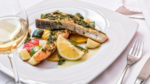 a white plate of food with fish and vegetables at Hotel Brückenwirt in Novacella