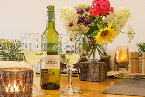 a bottle of wine and two glasses on a table with flowers at Moderne Ferienwohnung Nähe Bad Griesbach, Haarbach in Haarbach