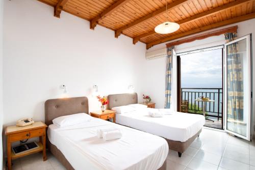 two beds in a room with a balcony at Hotel Korakakis Beach in Finikounta