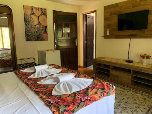 a room with a bed with pillows and a television at Pousada Penedo in Penedo