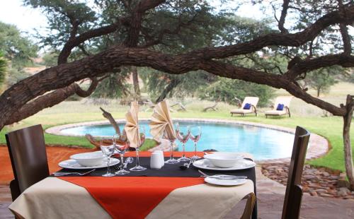 a table with wine glasses on it next to a pool at Camelthorn Kalahari Lodge in Hoachanas