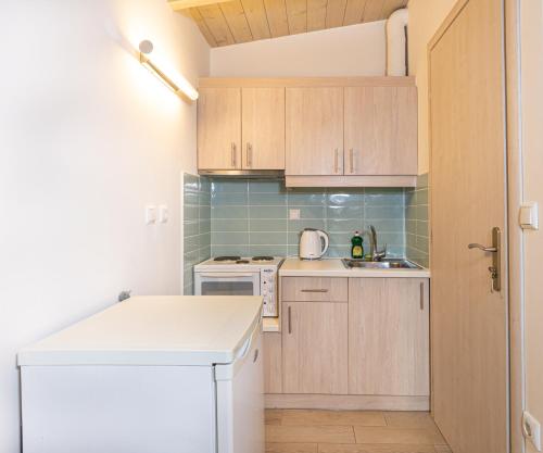 una pequeña cocina con armarios de madera y fregadero en Apartments Korakakis Beach, en Finikounta