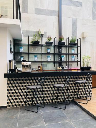 a restaurant with a counter with chairs and plants at Fraga Hotel Boutique in Irapuato