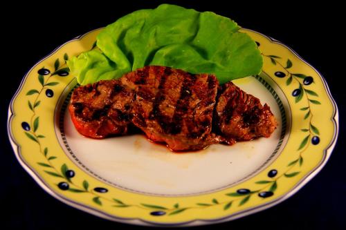 a piece of steak on a plate with lettuce at La Favorita Apricale B&B & Ristorante in Apricale