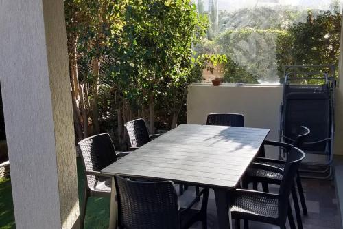 einen Holztisch und Stühle auf einer Terrasse in der Unterkunft Particulier loue T3 en rez de jardin à 30 mètres de la plage avec un double box in La Ciotat