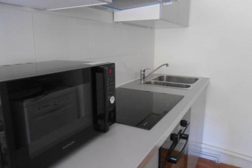 a kitchen with a microwave and a sink at Particulier loue T3 en rez de jardin à 30 mètres de la plage avec un double box in La Ciotat