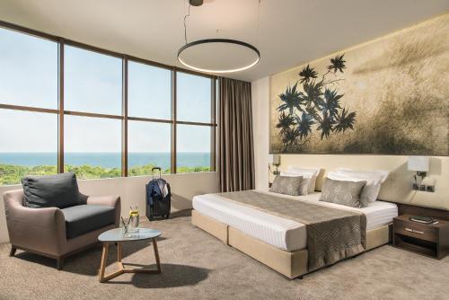 une chambre avec un lit, une chaise et des fenêtres dans l'établissement Rosslyn Dimyat Hotel Varna, à Varna