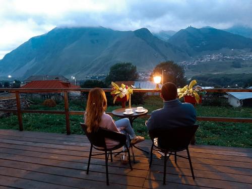 a man and a woman sitting at a table on a deck at Guesthouse Elli & Cottages in Stepantsminda