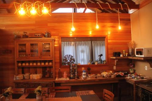 a kitchen with wooden walls and a table and a window at Pousada Vila dos Butias in Urubici