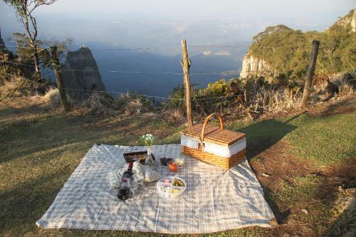 a picnic table with a basket and a bottle of wine at Pousada Vila dos Butias in Urubici