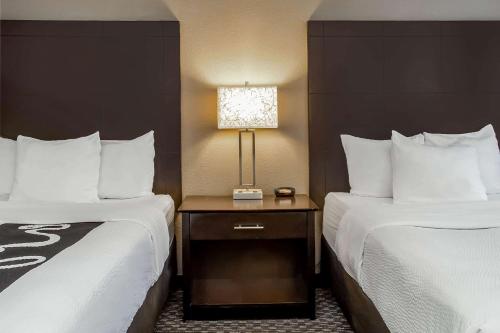 a hotel room with two beds and a table with a lamp at La Quinta Inn by Wyndham Oshkosh in Oshkosh