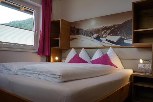 Schlafzimmer mit einem Bett mit rosa und weißen Kissen in der Unterkunft Bergfink apartments in Flachau