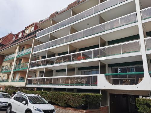 an apartment building with cars parked in front of it at Le Saint Amand, studio cabine, agréable terrasse sud in Le Touquet-Paris-Plage