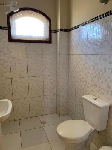 a bathroom with a toilet and a sink and a window at Pousada Bertimar in Bertioga