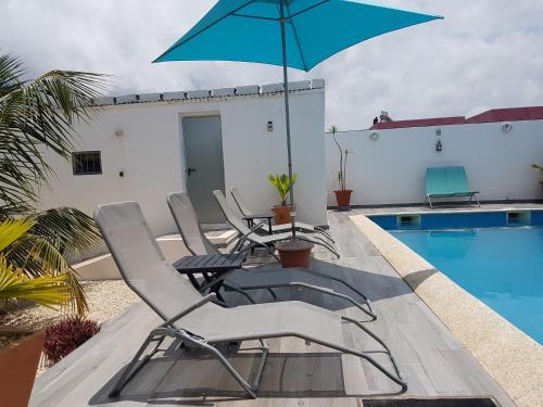 a patio with chairs and an umbrella next to a swimming pool at African Jaja villa Piscine-Climatisation in Poponguine