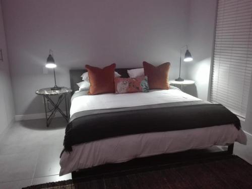 a bedroom with a large bed with orange pillows at EGRETS` ĂRK in Gansbaai