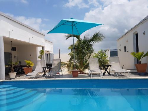 a pool with chairs and a blue umbrella at Villa JAJA Piscine-Climatisation in Poponguine