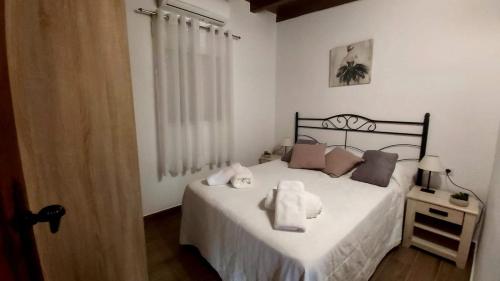 een slaapkamer met een bed met witte lakens en kussens bij Casa Rural La Resbala - Casa Verde in La Orotava