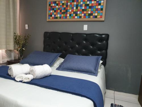 a bed with a black headboard and two rolled towels at Pousada Solar dos Cavaleiros Mendes in Macaé