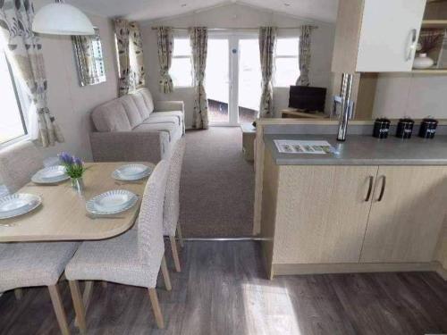 a kitchen and living room with a table and a couch at Cosy caravans Sandhills 213 Butlins Skegness resort in Ingoldmells