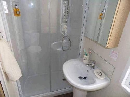 a white bathroom with a shower and a sink at Cosy caravans Sandhills 213 Butlins Skegness resort in Ingoldmells