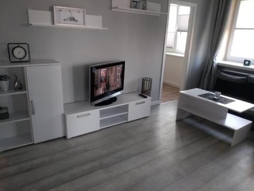 - un salon avec une télévision sur un centre de divertissement blanc dans l'établissement Apartament Centrum, à Radom