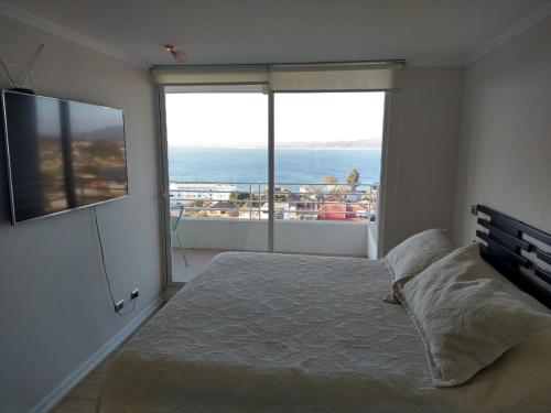 een slaapkamer met een bed en uitzicht op de oceaan bij DEPARTAMENTO EDIFICIO MARES DE MONTEMAR in Concón