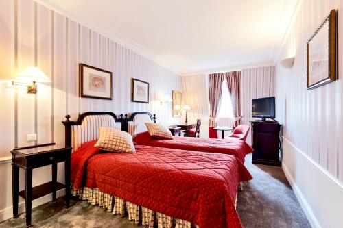 a hotel room with two beds and a television at Golden Tulip Washington Opera in Paris