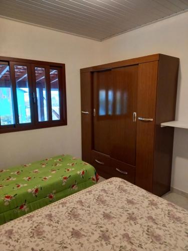 um quarto com uma cama, uma cómoda e um armário em Casa Lagoa e Praia Rosa na Praia do Rosa
