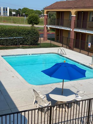 a pool with two chairs and an umbrella at Super 8 by Wyndham Midwest City OK in Midwest City