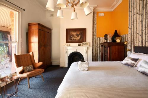 a bedroom with a bed and a chair and a fireplace at Lascelles Ballarat in Ballarat