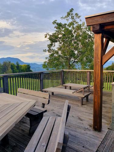 a wooden deck with picnic tables and a fence at Gozdarjeva koča nad Rimskimi Toplicami in Dol pri Hrastniku