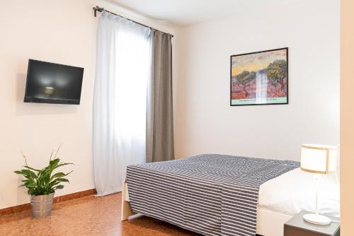 - une chambre avec un lit et une télévision murale dans l'établissement Marinali Rooms, à Bassano del Grappa