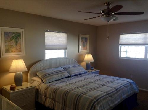 a bedroom with a bed with a ceiling fan and two windows at Island House Beach Resort 26 in Point O'Rocks