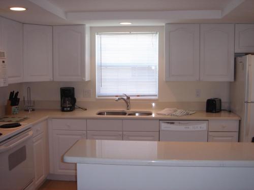 a kitchen with white cabinets and a sink and a window at Island House Beach Resort 26 in Point O'Rocks